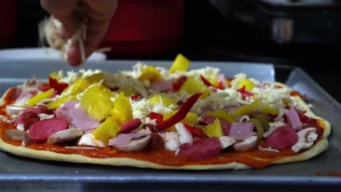 Closeup putting parmesan cheese ingredients on homemade pizza in kitchen with Видео 164581877