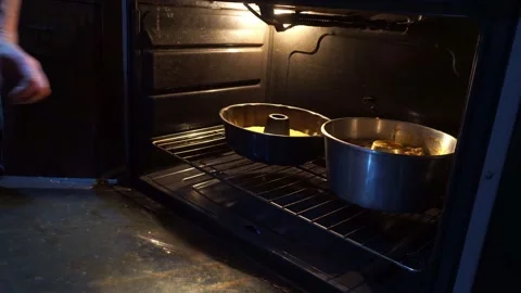 Closeup putting two homemade cake molds in an oven Stock Footage 155273775