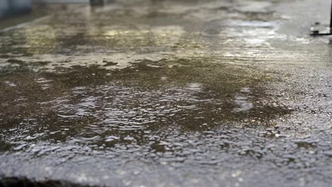 Closeup of rain drop splash into water puddle on wet outdoor concrete ground Video stock 342612137