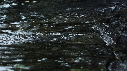 Closeup of rain falling on an old granite stone floor, moving camera Stock Footage 98053815