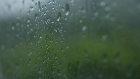 Closeup of raindrops slowly sliding down glass window with blurred city Stock Footage 320111648