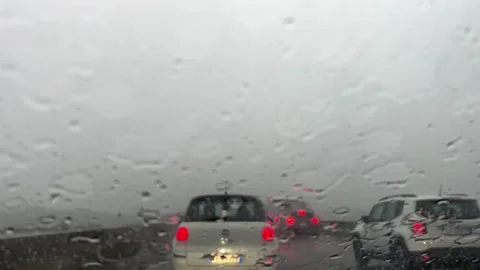 Closeup of rainy weather on windshield with car lights Stockbeeldmateriaal 280876112