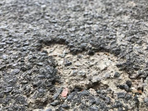 Closeup of a random cordiform heart shape imprint on coarse cemented tar asphalt Stock Photos