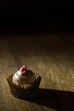 Closeup of raspberry topped chocolate praline on a wooden shelf Stock Photos