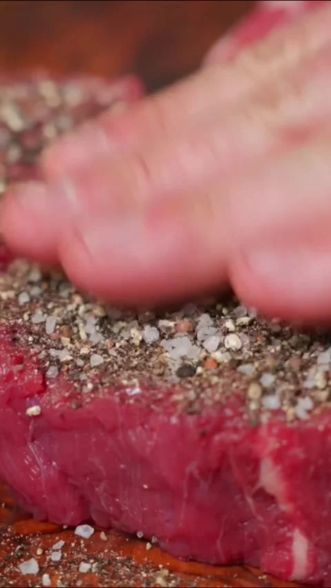 Closeup of raw beef steaks being seasoned with salt and pepper Stock Footage 336656803