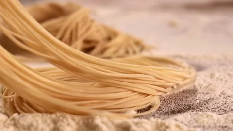 Closeup on raw pasta in white flour on a wooden table Stock-Footage 149067562