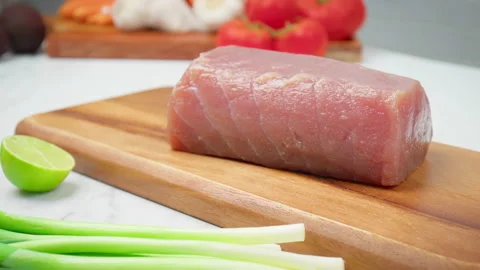 Closeup of raw Tuna Yellowfin on a table with greens and vegetables in 4K. Stock Footage 154334627