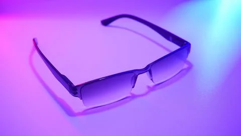 Closeup of rectangular optical glasses on a flat surface with a neon purple ligh Foto stock