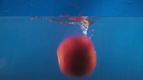 Closeup of red apple falling into water on the blue backgrond slow motion Stock Footage 75787838