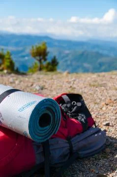 Closeup Red Backpack With sleeping mat Lays on rocky ground in front of mountain Stock Photos