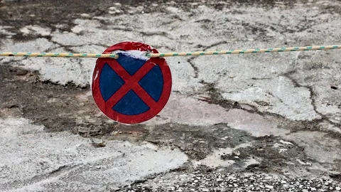 Closeup of a red blue no stopping traffic sign blocking walkway swaying on .. Видео 333767116