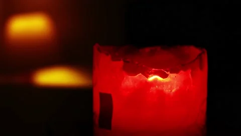 Closeup of a red candle lit with fire flaming in the dark of a restaurant at Stock Footage 164572072
