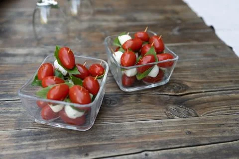 Closeup of red cherry tomatoes, fresh basil and mozzarella cheese, appetizer. Stock Photos