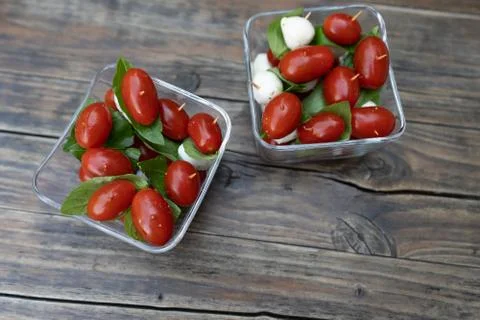 Closeup of red cherry tomatoes, fresh basil and mozzarella cheese, appetizer. Stock Photos