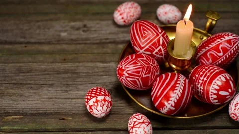 Closeup Red easter eggs with folk pattern lay around and on brass candlestick Stock Footage 127887515