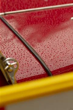 Closeup of red painted metal panel with raindrops and diagonal chrome trim Stock Photos