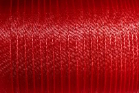 Closeup red polyester thread spool with reflective textile fiber texture Stock Photos