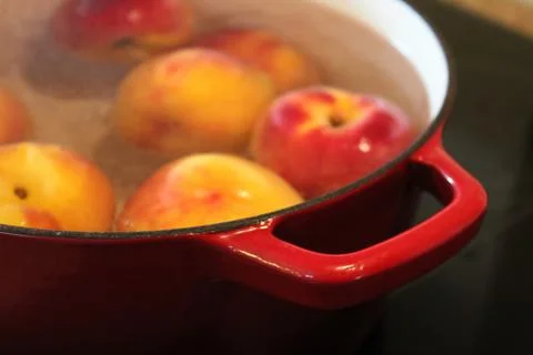 Closeup of a red pot handle while blanching peaches Stock Photos
