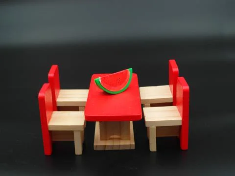 Closeup of a red tiny table and chairs on a black background 스톡 사진
