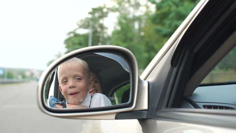 Closeup reflection in the side mirror in the car of a little boy with his mother Stock Footage 115115735