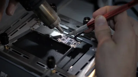 Closeup repairman warms iphone U2 charger controller Stock Footage 104655631