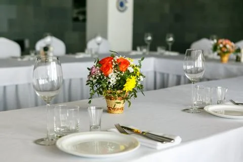A closeup of restaurant table set with colourful flower bouquet in wicker wase Stock Photos