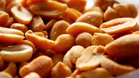 A closeup of roasted and salted peanuts falling on a pile Stock Footage 134905420