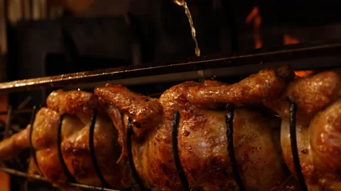 Closeup of a roasted chickens on spit grilled over wood fire on big bbq barbecue Stock Footage 199262390