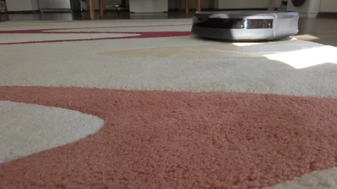 Closeup of a robotic vacuum cleaner cleans the carpet in the living room. Stock Footage 119161676