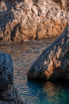 Closeup rocky rough gray cliffs of Adriatic seashore, light blue sea Stock Photos