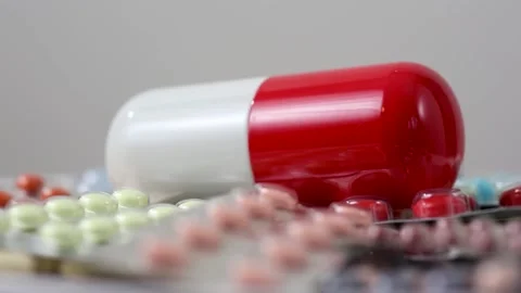 Closeup of rotating big pill on pile of colourful pills in blister Stock Footage 288107119