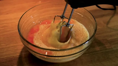 Closeup of rotating electric mixer beaters whipping a pale egg mixture in a.. Stock Footage 340897304
