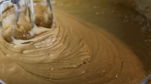 Closeup of rotating electric mixer beaters blending thick, smooth batter in.. Stock Footage 340897414
