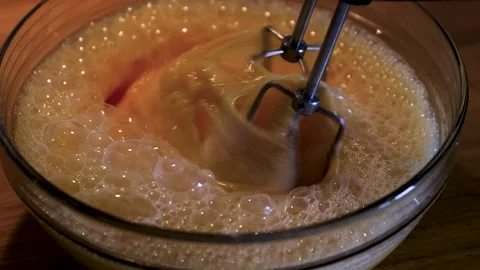 Closeup of rotating electric mixer beaters whipping a pale egg mixture in a.. Stock Footage 340897468