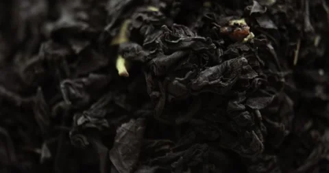 Closeup of rotating pile of dried black large-leaves herbal tea with fruits. Stock Footage 145446557