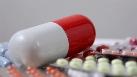 Closeup rotating shot of big pill on a pile of pills in their blister Stock Footage 123479205
