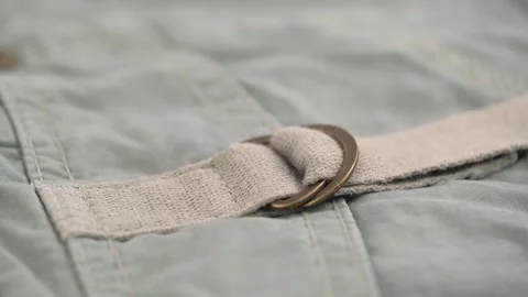 Closeup rotation, two metal half-rings on canvas belt of khaki trousers pocket. Stock Footage 254180920