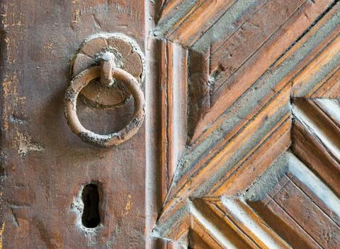 Closeup of rusted ring door knob over an aged decorated wooden door Stock Photos