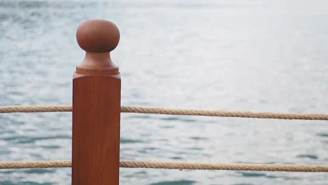A closeup of a rustic wooden post with nautical rope by the peaceful waters edge Stock Footage 291506384