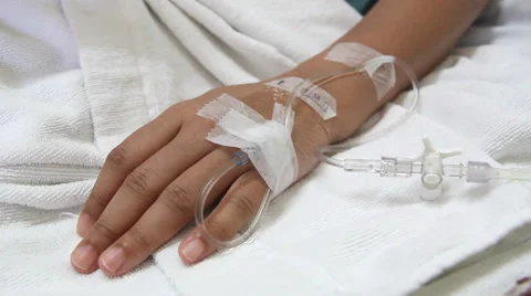 Closeup saline drip into patient hand on bed in hospital Stock Footage 27828324