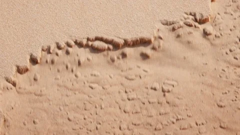Closeup of sand falling in on itself forming small clumps and dissolving Vídeo Stock 76935842