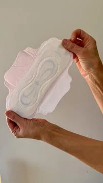 Closeup of a sanitary pad held by two hands against a neutral background, sho 스톡 사진