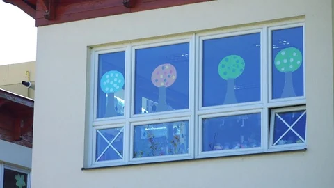 Closeup on school windows decorated with children's creations on a sunny day Vídeo Stock 79521317