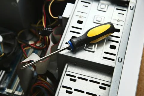 A closeup of a screwdriver on the computer components in an open case under t Stock Photos