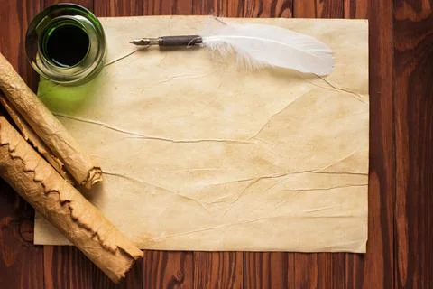 Closeup of scroll and quill near ink-pot on wooden table Stock Photos