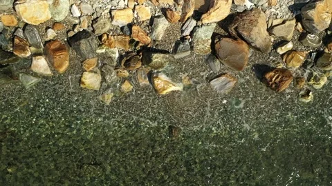 Closeup of sea waves flowing around the rocks on the shore Stock Footage 223415568