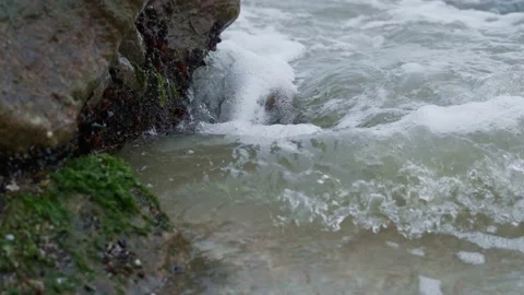 Closeup of sea waves with foam running ashore and hitting rocky boulders Stock Footage 162226815