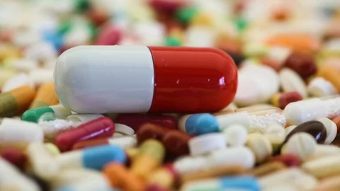 Closeup seamless loop of pills spinning with large one Video stock 97054092