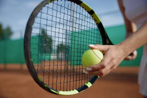 Closeup selective focus on ball and tennis racket in female hand Stock Photos