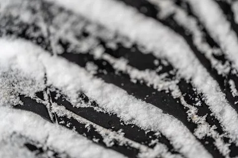 Closeup selective focus on snow packed in an all-weather tire tread. Stock Photos